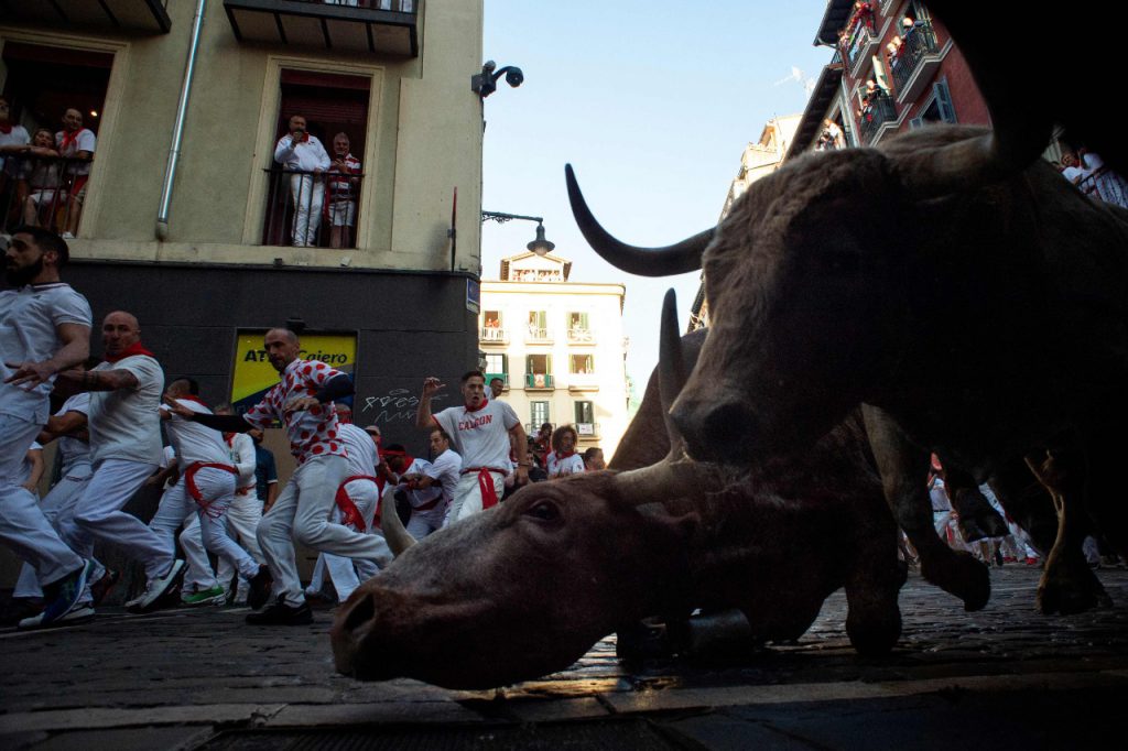 Corredores y toros toman una curva durante el primer encierro de las fiestas de San Fermín. Foto: AFP.