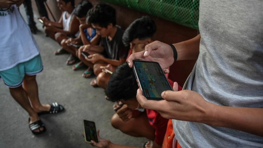 Jóvenes filipinos utilizan sus teléfonos móviles para jugar a 'Axie Infinity' en un callejón de Malabon, suburbio de Manila. Foto: AFP.