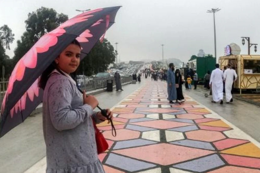 Una mujer pasea bajo un paraguas en Al Namas en Arabia Saudita. Foto: AFP.