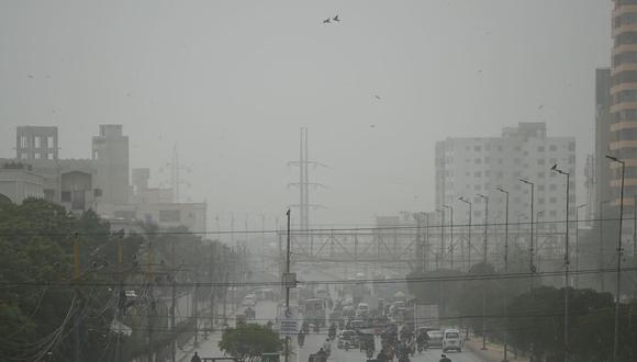 Los viajeros se abren camino en medio de una atmósfera polvorienta a lo largo de una calle transitada durante un día ventoso y de gran concentración de metano. Foto: AFP.
