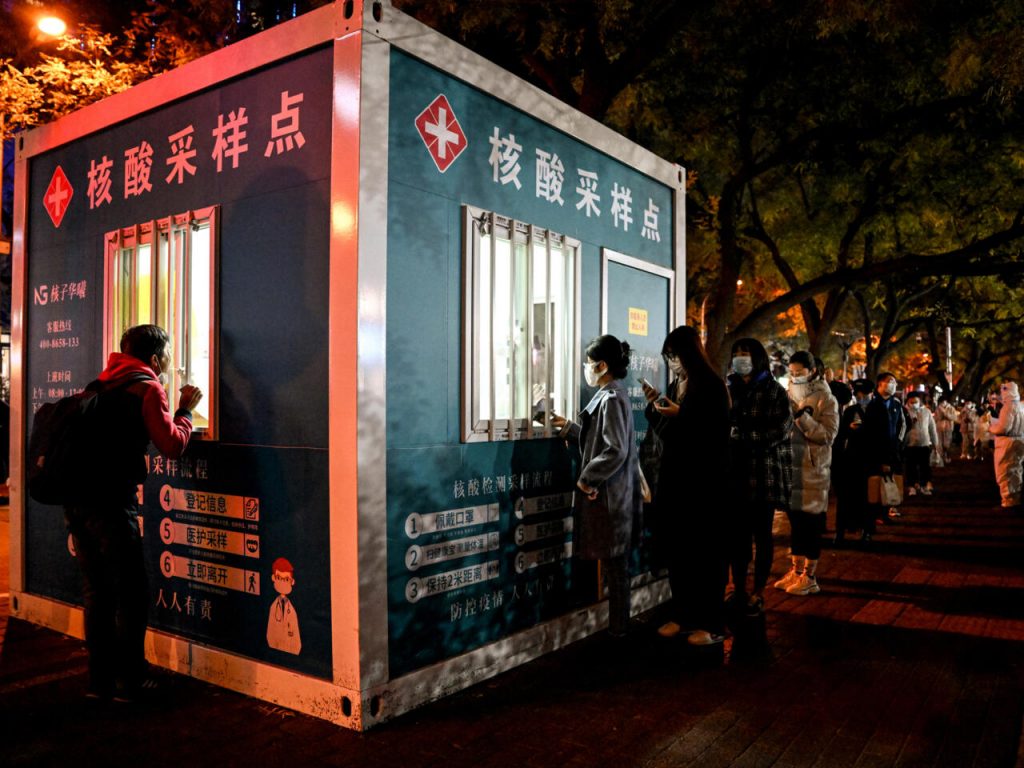 Decenas de personas guardan cola ante un punto de reparto de pruebas de detección del COVID-19, el 15 de noviembre, en Pekín. Foto: AFP.