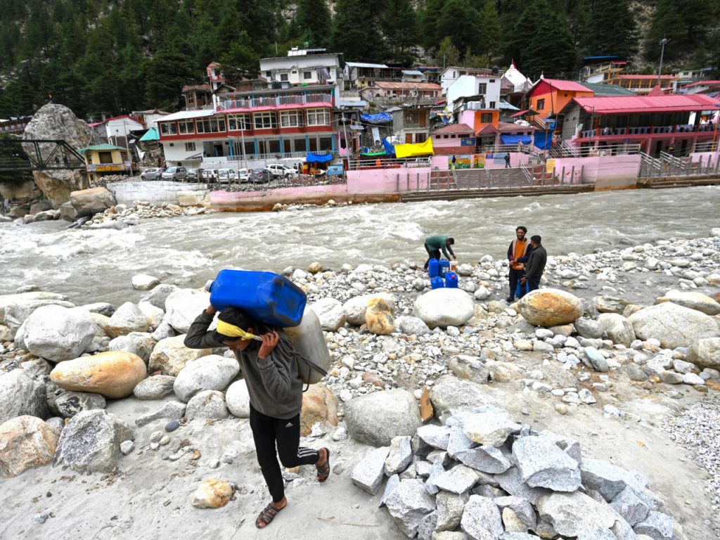 Unos trabajadores cargan con bidones llenos de agua derretida del glaciar Gangotri, fuente primaria para el río sagrado Ganges, el 15 de septiembre de 2022 en Uttarakhand, India. Foto: AFP.