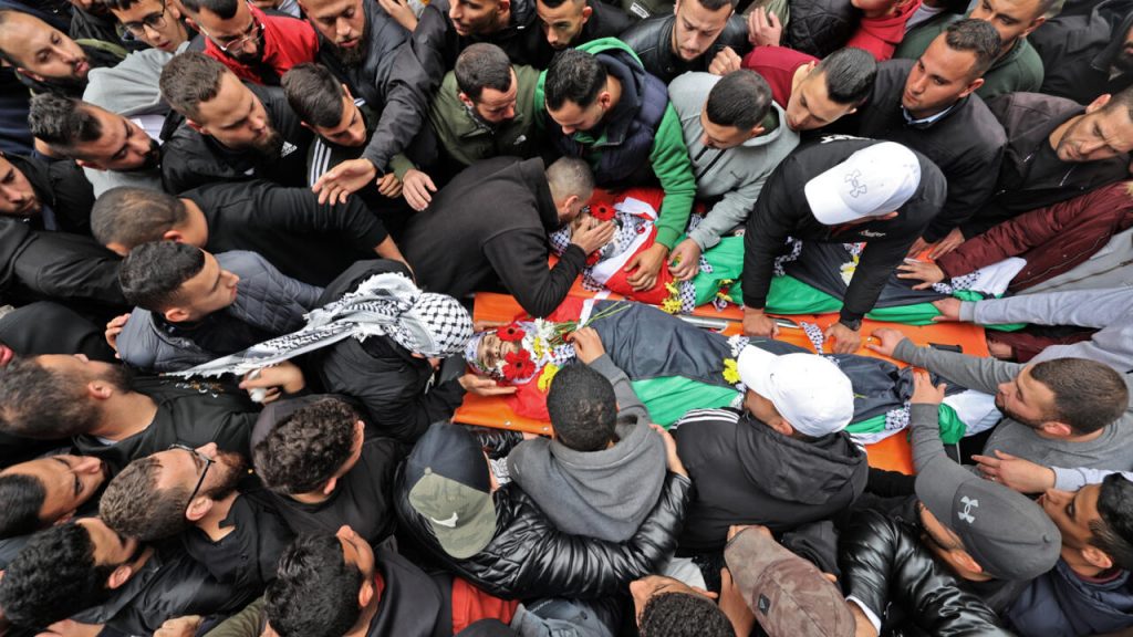 Una multitud rodea los cadáveres de dos palestinos muertos en enfrentamientos con las fuerzas israelíes, el 29 de noviembre de 2022 en la ciudad cisjordana de Ramala. Foto: AFP.
