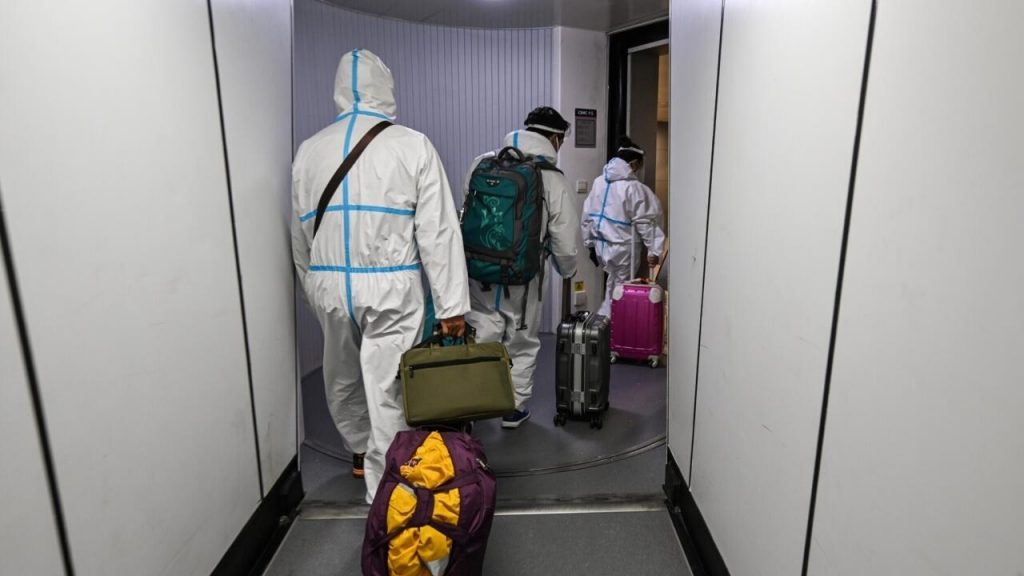Pasajeros con trajes de protección desembarcan en el aeropuerto de Shanghái tras llegar en avión desde París, el 18 de enero de 2022. Foto: AFP.