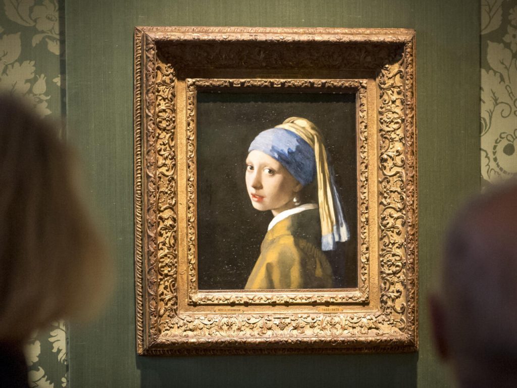 Unos visitantes contemplan el cuadro 'La joven de la perla', de Johannes Vermeer, el 27 de octubre de 2022 en el museo Mauritshuis de La Haya. Foto: AFP.