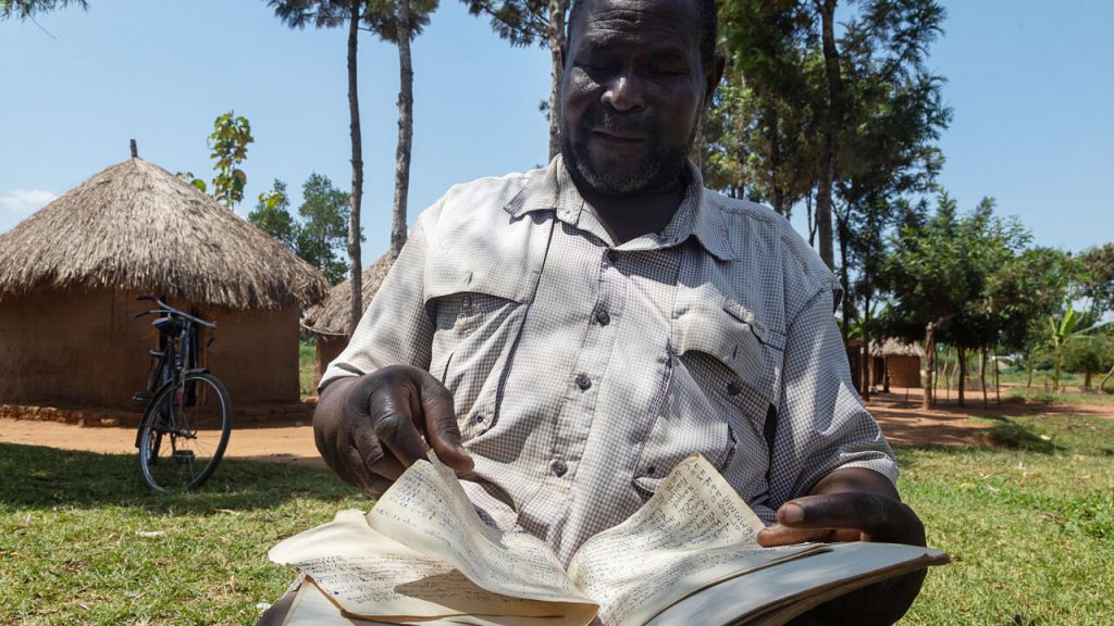 Musa Hasahya Kesera revisa el cuaderno donde anota detalles sobre su extensa familia, el 17 de enero de 2023 en Butaleja, Uganda. Foto: AFP.