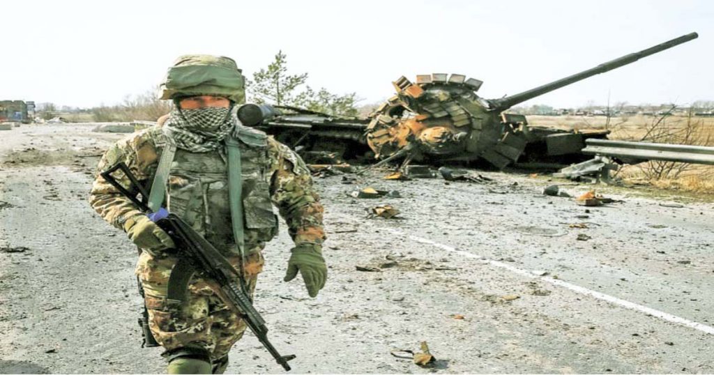 Un soldado ucraniano delante de un tanque ruso inutilizado.