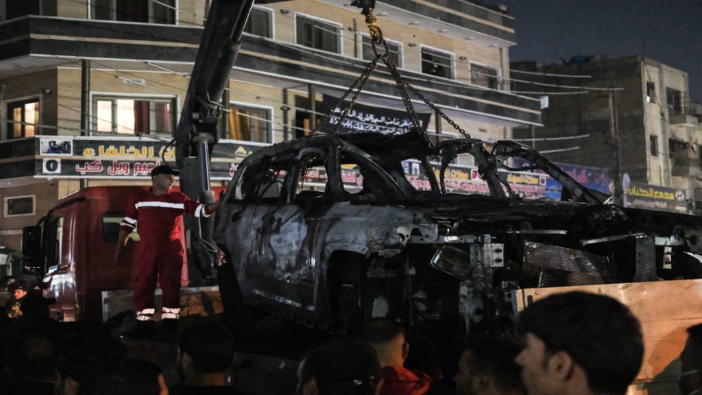 La gente observa cómo un vehículo que fue alcanzado por un ataque con drones, que supuestamente mató a tres personas, incluidos dos líderes de un grupo pro-Irán, es llevado en Bagdad el 7 de febrero de 2024.