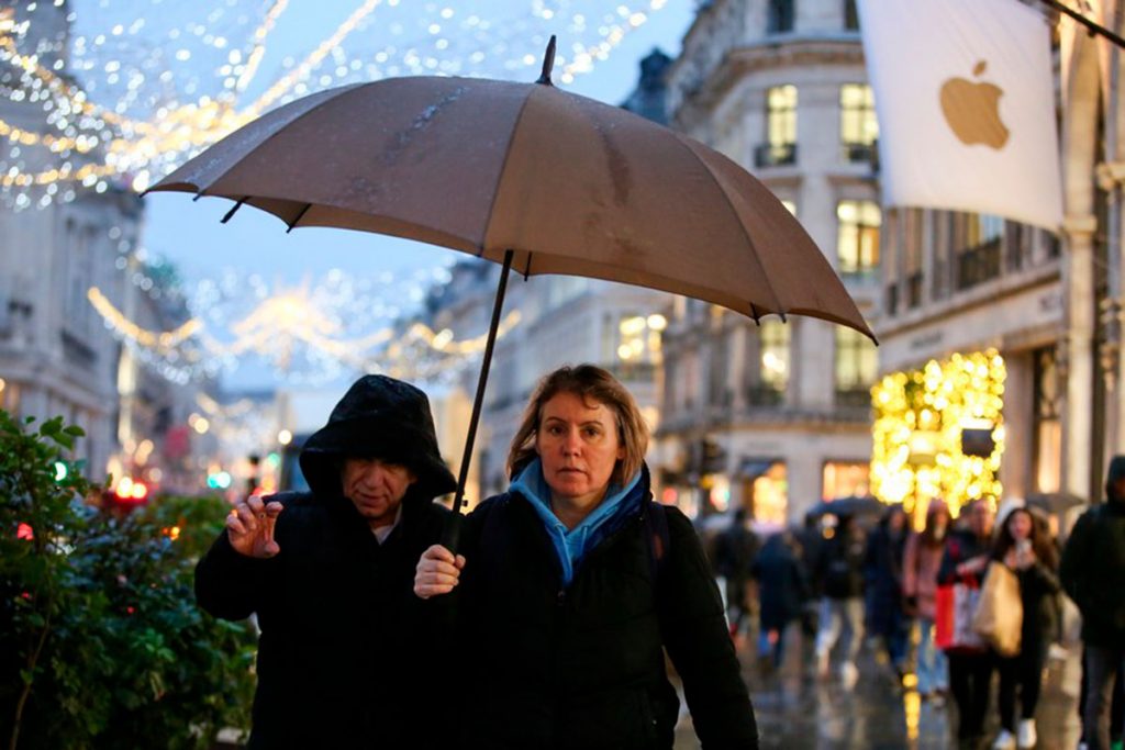 Una mujer joven con un paraguas en una chaqueta de lluvia usa una
