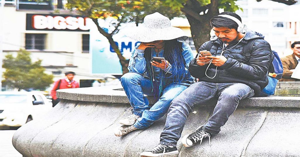Dos jóvenes manejan sus celulares en el El Prado, La Paz.